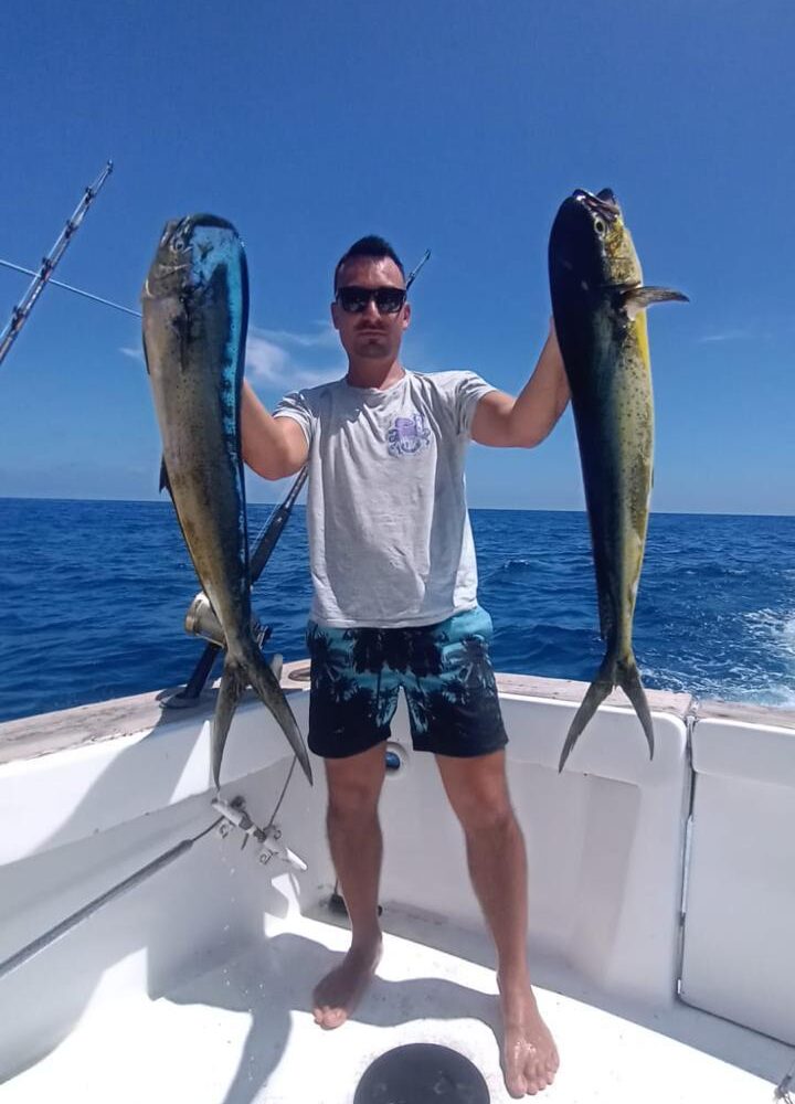 Man holding two large fish while fishing in Punta Cana waters