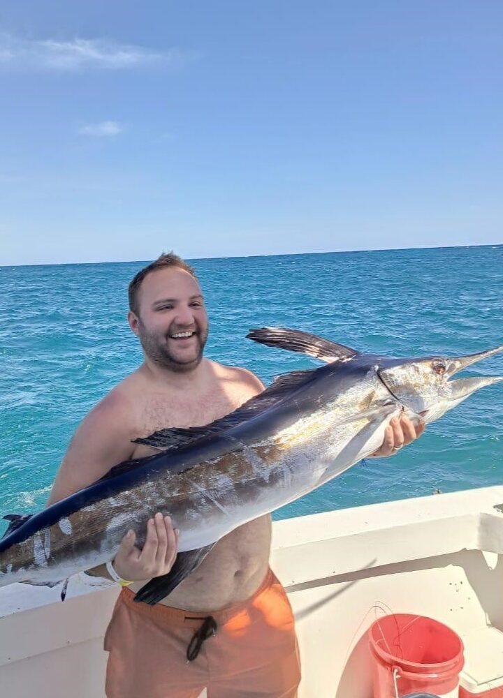 Man proudly holding a large marlin while fishing in Punta Cana.