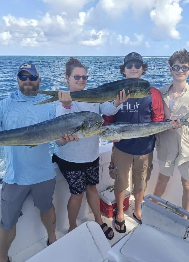 Group of four holding large fish on a boat in Punta Cana, showcasing a successful fishing excursion.