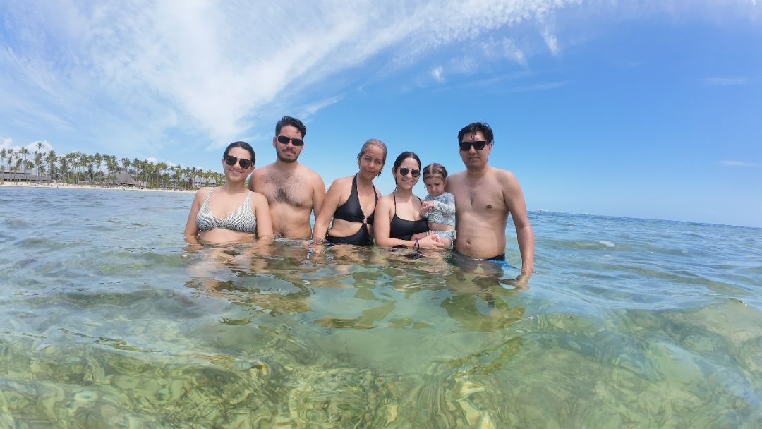 Family enjoying a sunny day in Punta Cana's clear waters with palm trees in the background.